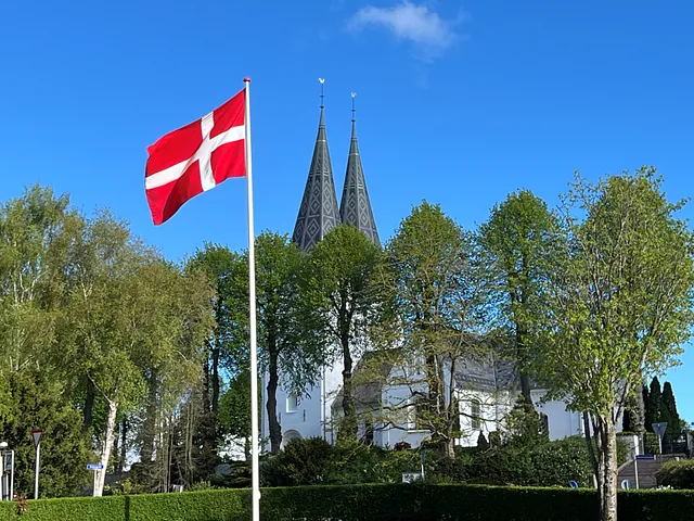 Flag ved sognegården og Broager kirke i baggrunden